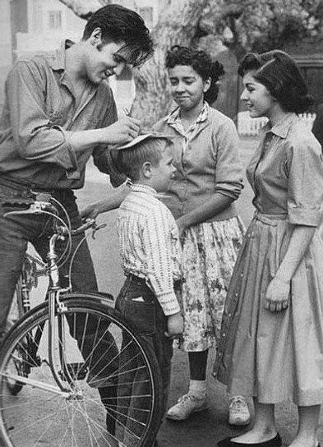 Elvis firmando autógrafos sobre su bicicleta, en la década de los 50.